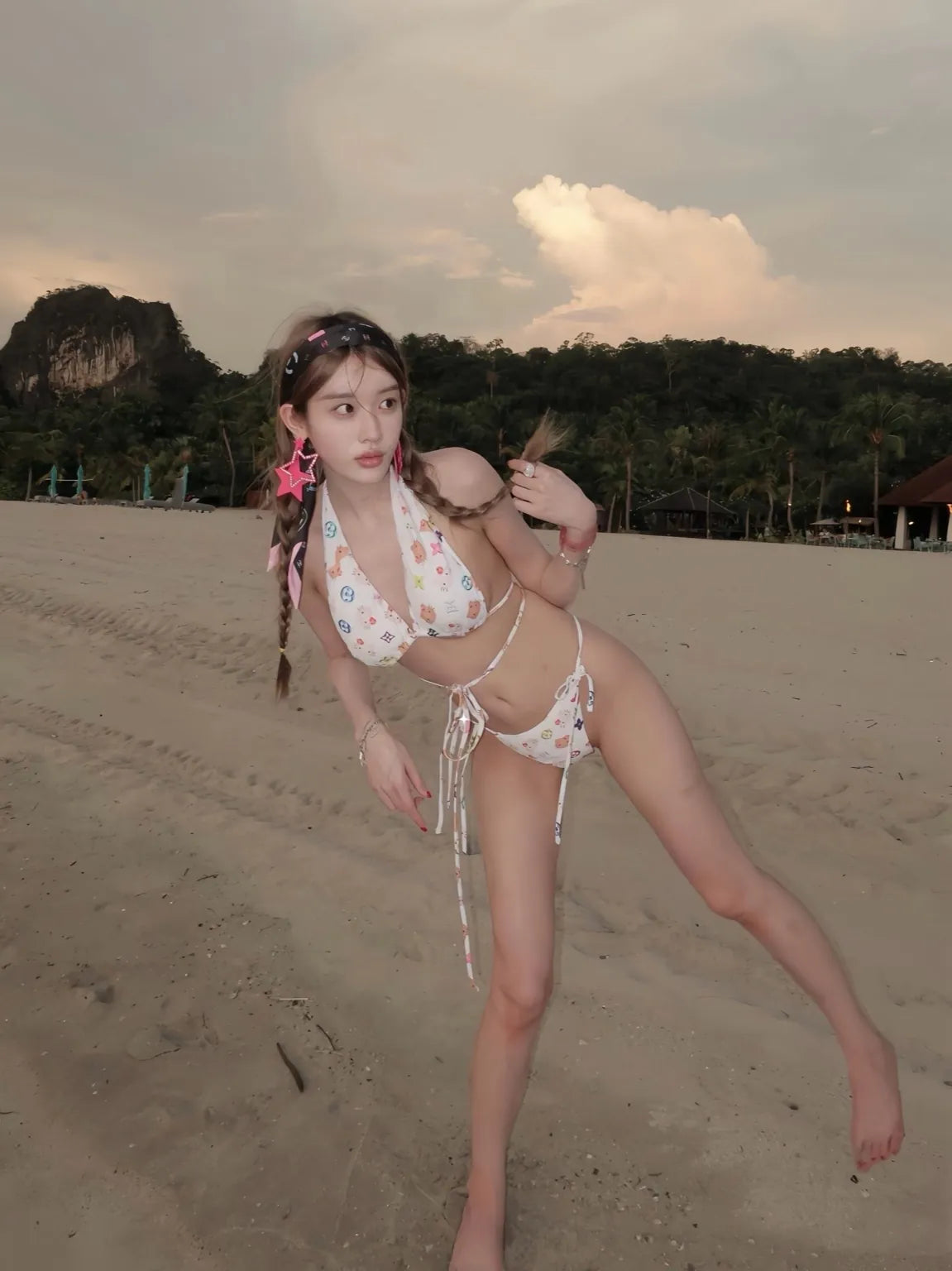 Woman in a Hello Kitty bikini standing on a beach with mountains in the background